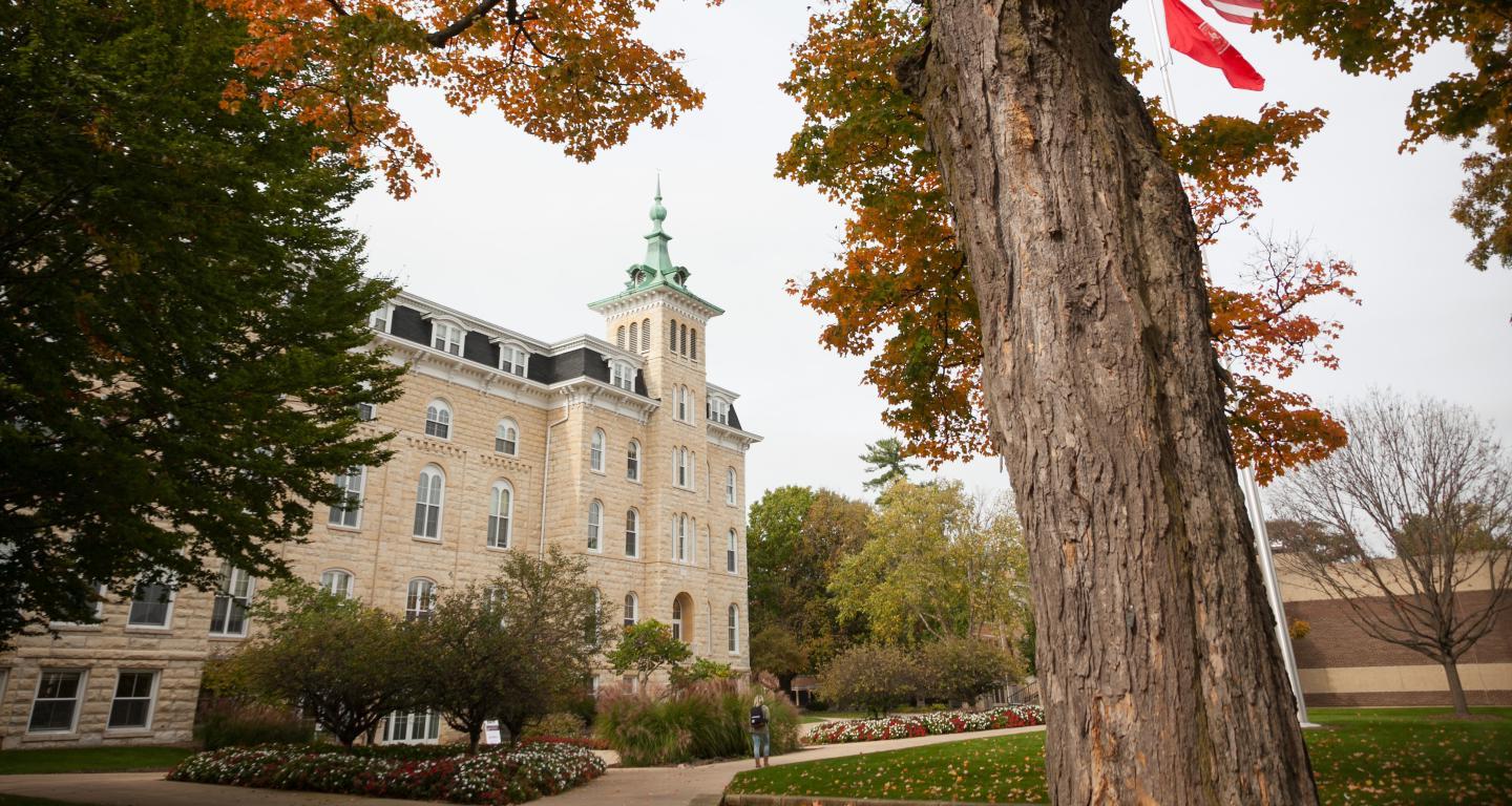 old main in the fall between some trees